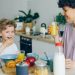 Young woman drinking orange juice while son eating cereal at table in kitchen